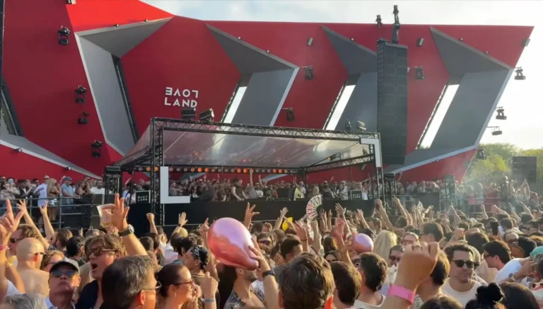 Feestvierders met een roze ballon en een waaier voor het rode Loveland-podium, overdag