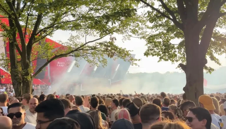 Dichte menigte in de rook, met een deel van het rode Loveland-podium zichtbaar tussen de bomen