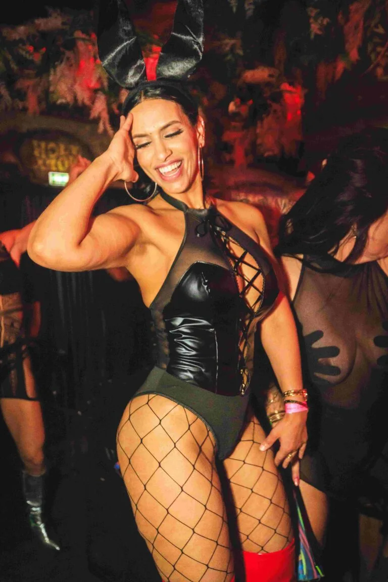 Een gast in een speelse feestoutfit met konijnenoortjes lacht tijdens het dansen.